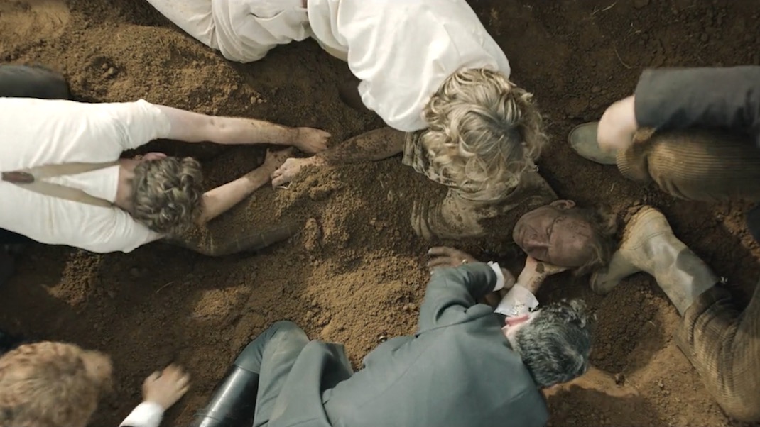 People rescuing Ralph Fiennes, who is buried in dirt, in the movie THE DIG