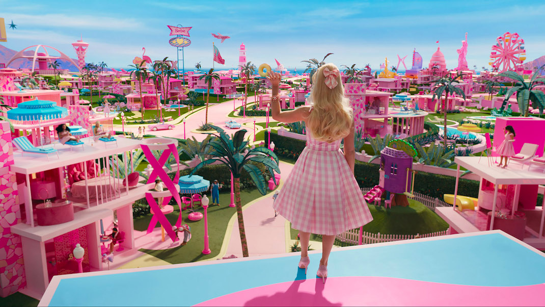 From atop her dream house, Barbie (Margot Robie) surveys her candy-colored realm in BARBIE (2023)