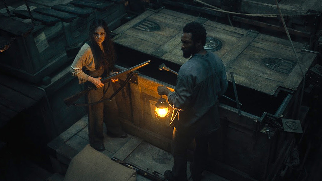 Anna (Aisling Franciosi) and Clemens (Corey Hawkins) investigate the ship's dark cargo hold in THE LAST VOYAGE OF THE DEMETER