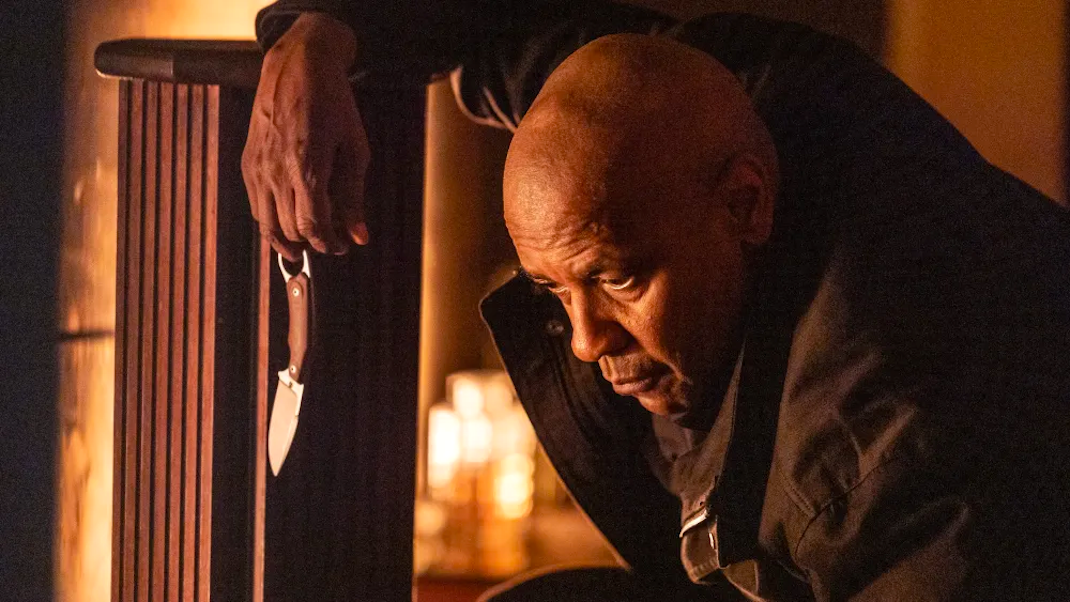 Denzel Washington, leaning on a bannister and staring down, dangles a knife in THE EQUALIZER 3.